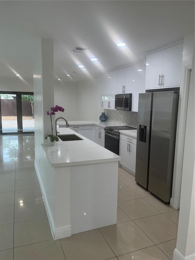 kitchen with kitchen peninsula, sink, decorative backsplash, appliances with stainless steel finishes, and white cabinetry