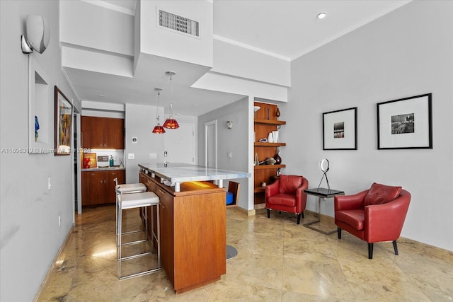 kitchen featuring decorative light fixtures, a center island, light stone counters, and a breakfast bar area