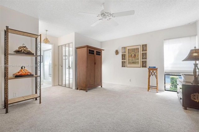 interior space featuring ceiling fan, light colored carpet, and a textured ceiling