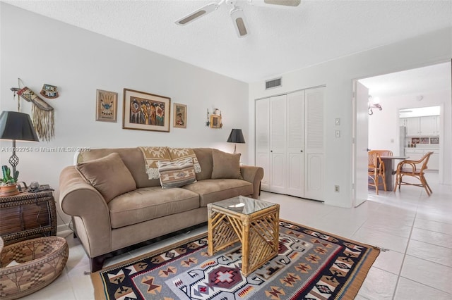 tiled living room with a textured ceiling and ceiling fan