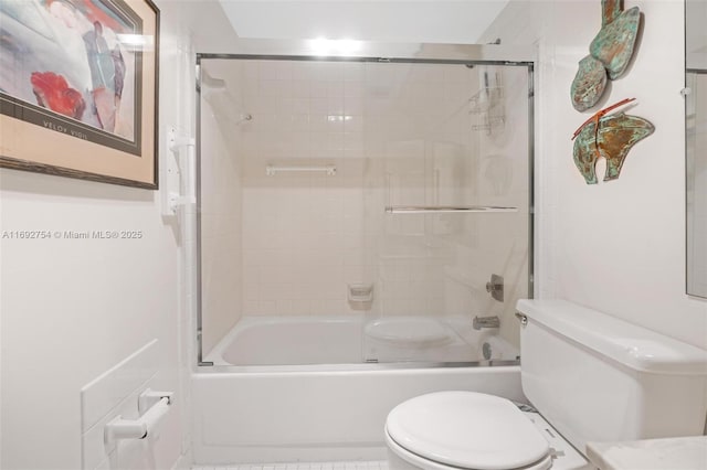 bathroom featuring toilet and bath / shower combo with glass door