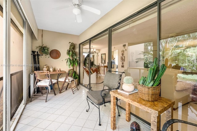 sunroom featuring ceiling fan with notable chandelier