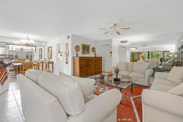 living room featuring ceiling fan with notable chandelier, light tile patterned floors, and a textured ceiling