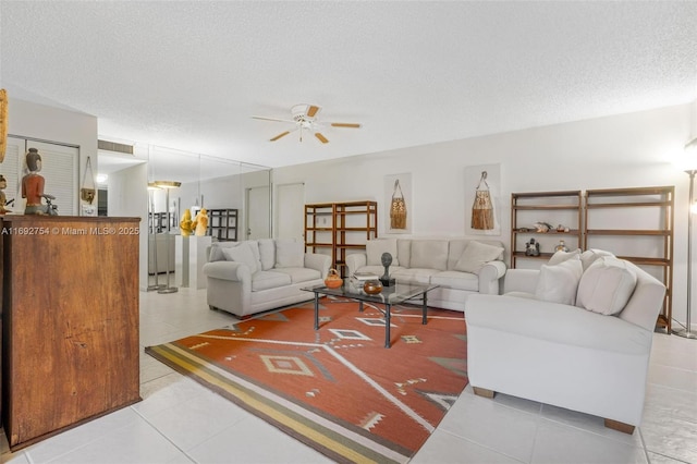 living room featuring light tile patterned floors, a textured ceiling, and ceiling fan