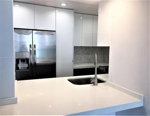 kitchen featuring white cabinets, stainless steel fridge with ice dispenser, decorative backsplash, and sink