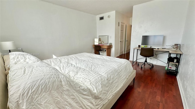 bedroom featuring a textured ceiling, dark wood-type flooring, and a closet