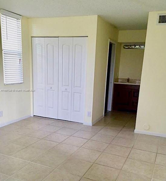 unfurnished bedroom with light tile patterned floors and a closet