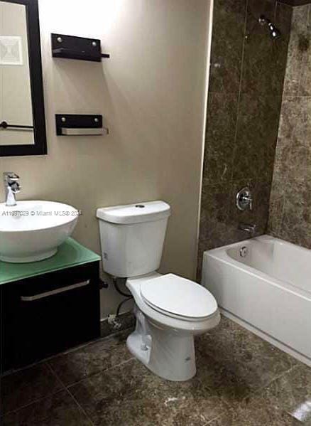 full bathroom featuring tile patterned flooring, tiled shower / bath combo, toilet, and vanity