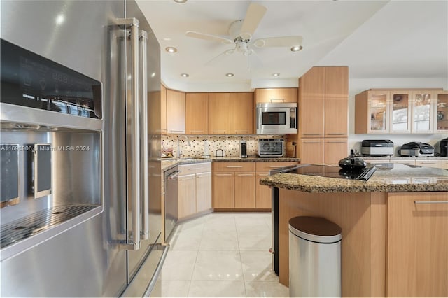 kitchen with decorative backsplash, light brown cabinetry, stainless steel appliances, ceiling fan, and stone counters