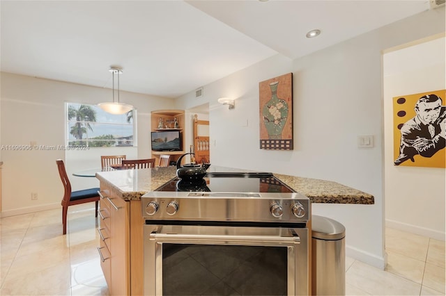 kitchen featuring light stone counters, a center island, stainless steel stove, and decorative light fixtures