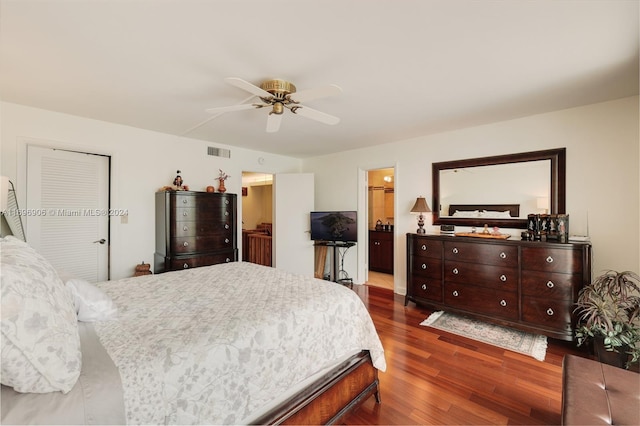 bedroom with dark hardwood / wood-style flooring, ceiling fan, and connected bathroom