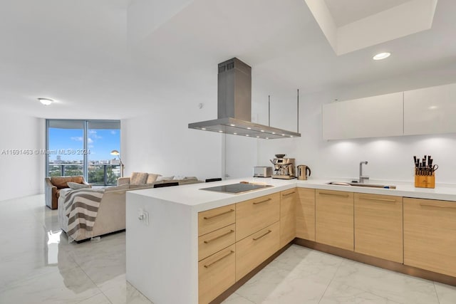 kitchen with sink, black electric stovetop, kitchen peninsula, island range hood, and light brown cabinetry