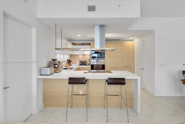 kitchen featuring kitchen peninsula, a kitchen breakfast bar, light brown cabinetry, double oven, and sink