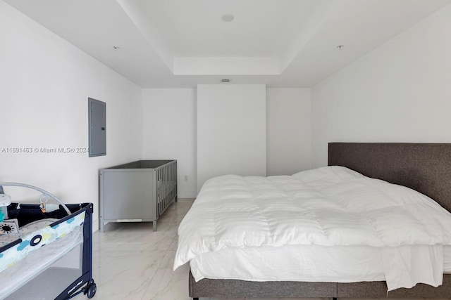 bedroom with electric panel and a raised ceiling