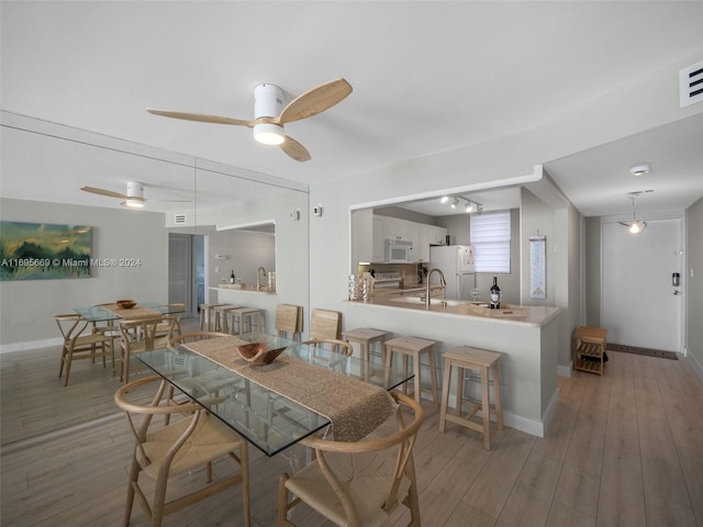 dining room with hardwood / wood-style floors, ceiling fan, and sink