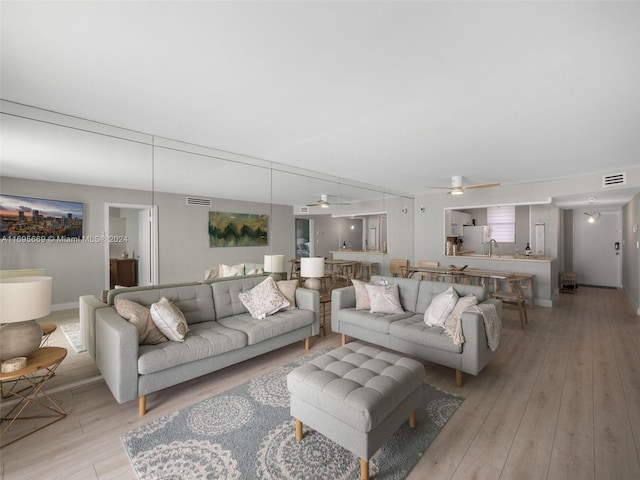 living room with light hardwood / wood-style flooring and ceiling fan