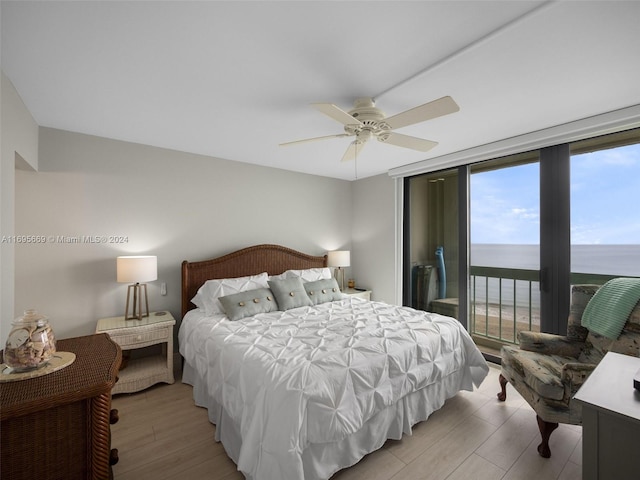 bedroom featuring access to exterior, a water view, ceiling fan, and light hardwood / wood-style floors