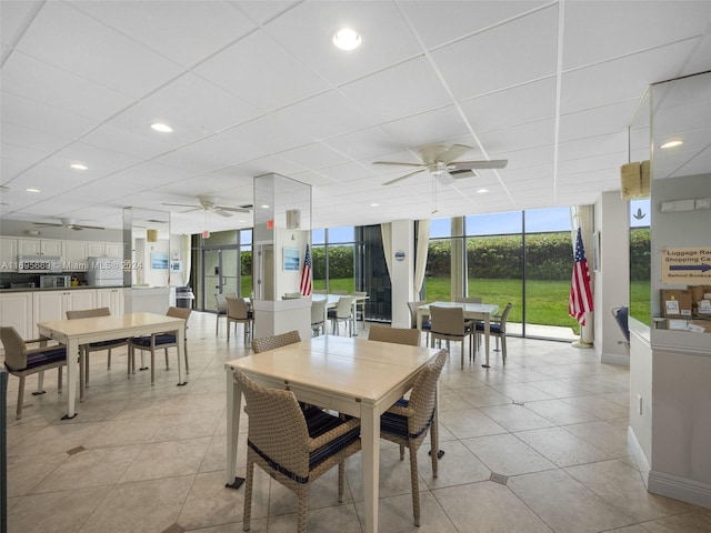 dining space featuring ceiling fan, light tile patterned flooring, and a wall of windows