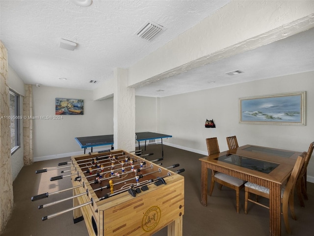 recreation room with a textured ceiling and dark carpet