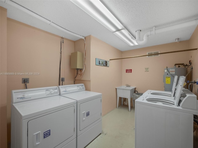 clothes washing area featuring electric water heater, independent washer and dryer, and a textured ceiling