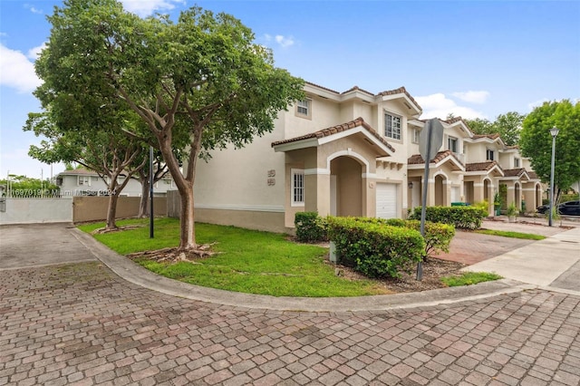 mediterranean / spanish-style home with a garage and a front lawn