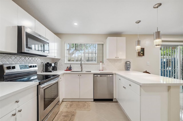 kitchen with kitchen peninsula, appliances with stainless steel finishes, a wealth of natural light, sink, and white cabinets