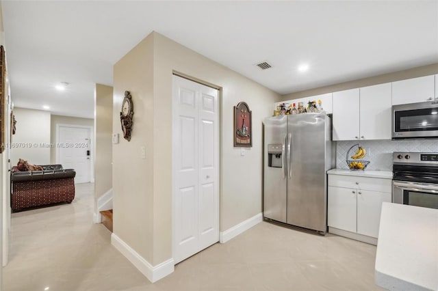 kitchen with white cabinets, light tile patterned floors, stainless steel appliances, and tasteful backsplash