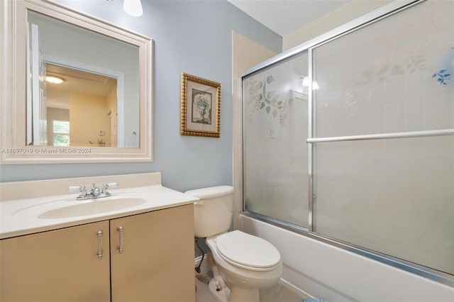 full bathroom featuring combined bath / shower with glass door, vanity, and toilet