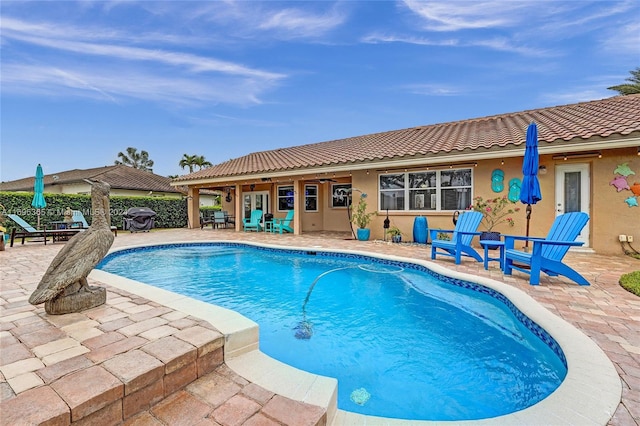 view of swimming pool with ceiling fan, a patio, and grilling area