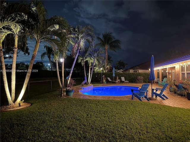 pool at twilight featuring a yard and a patio area