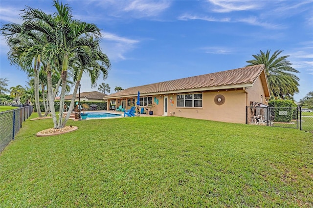 back of property with a fenced in pool and a yard