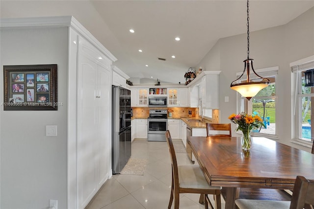 dining area with light tile patterned flooring, sink, and vaulted ceiling