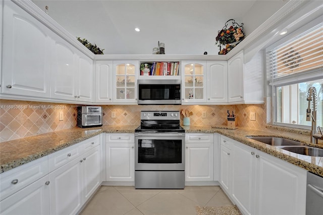 kitchen with white cabinetry, light tile patterned floors, stainless steel appliances, and light stone counters