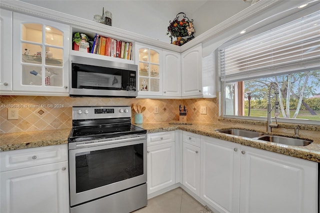 kitchen featuring tasteful backsplash, light stone counters, stainless steel appliances, sink, and white cabinets