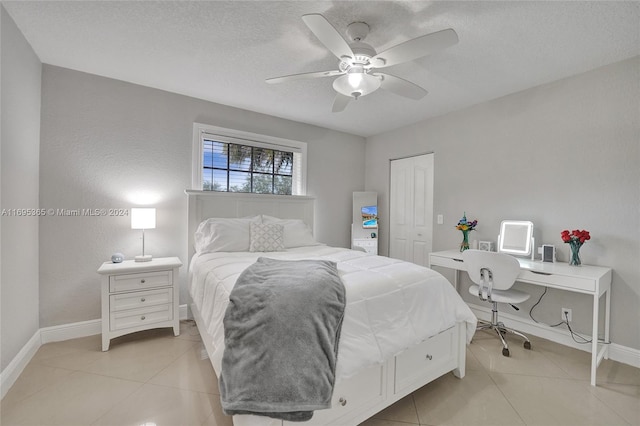 bedroom featuring ceiling fan, light tile patterned floors, a textured ceiling, and a closet