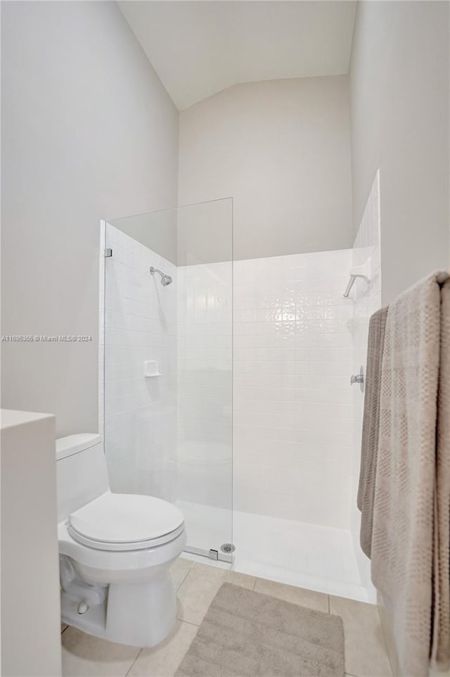 bathroom with tile patterned flooring, toilet, and tiled shower