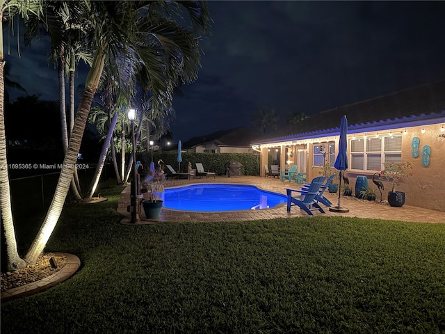 pool at twilight with a yard and a patio area