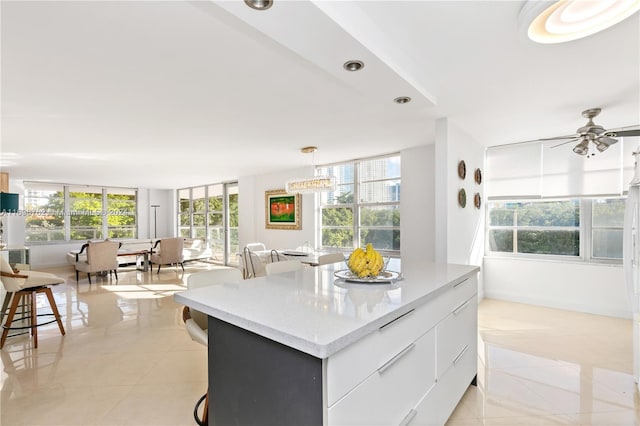 kitchen with ceiling fan, light tile patterned floors, decorative light fixtures, white cabinets, and a kitchen island