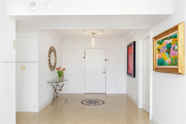 foyer entrance with ornamental molding and light tile patterned flooring