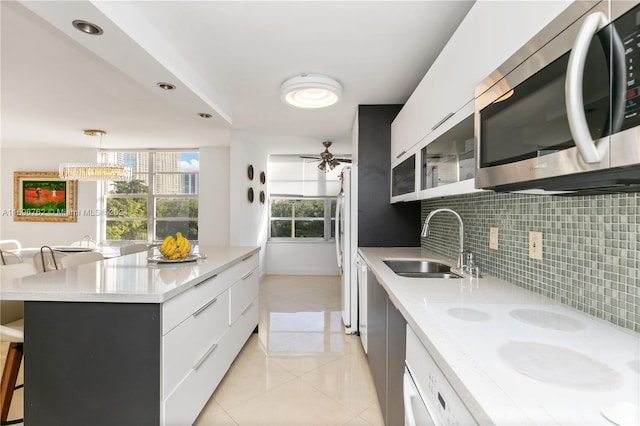 kitchen featuring white appliances, white cabinets, a kitchen breakfast bar, sink, and decorative light fixtures