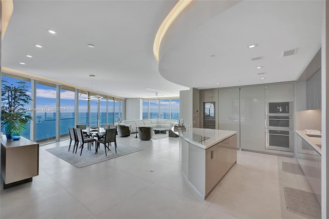 kitchen with light stone countertops, a water view, pendant lighting, and a wall of windows