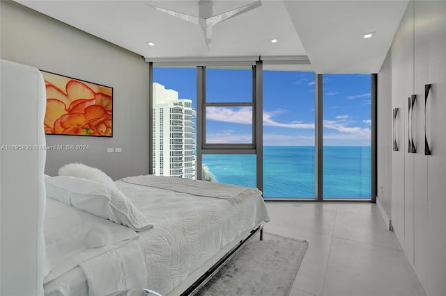 bedroom featuring access to exterior, a wall of windows, a water view, and ceiling fan