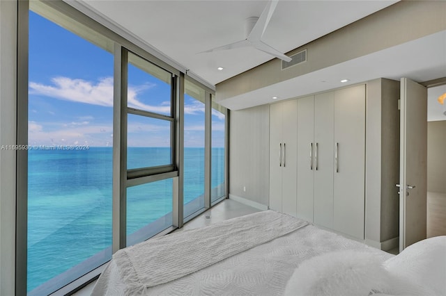 bedroom with expansive windows, a water view, and access to outside