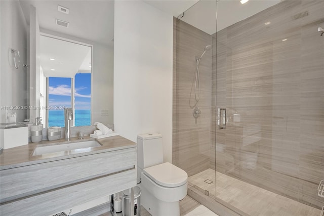 bathroom featuring toilet, a water view, a shower with door, and vanity