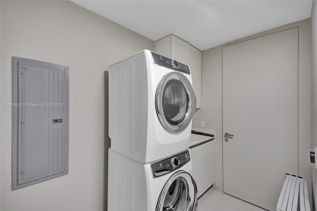 laundry area with electric panel and stacked washer / drying machine