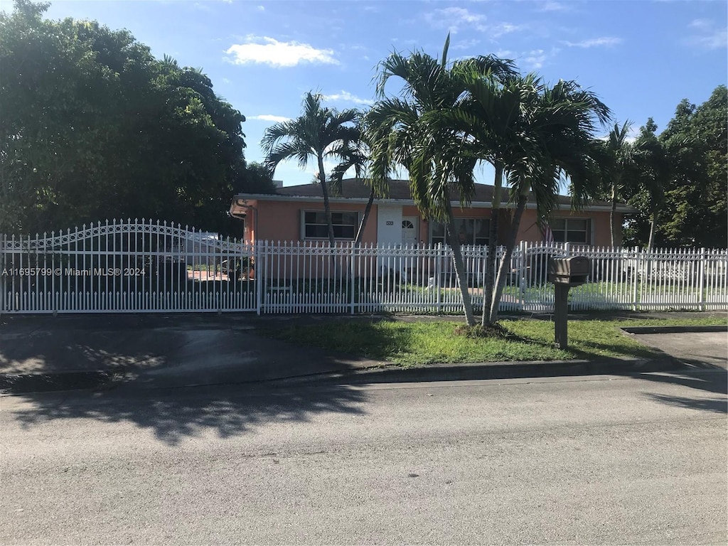 500 E 30th St, Hialeah, FL 33013 - view of property hidden behind natural elements with a fenced front yard, stucco siding, and a gate