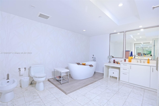 bathroom with vanity, toilet, a bidet, and a tub