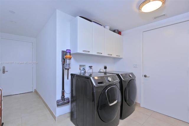 clothes washing area with cabinets, light tile patterned floors, and washer and clothes dryer