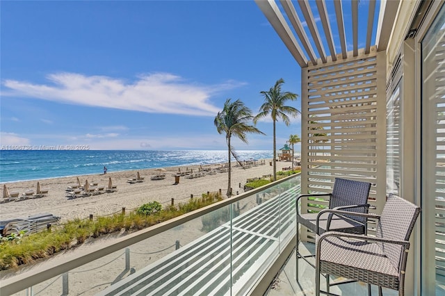 balcony with a water view and a view of the beach