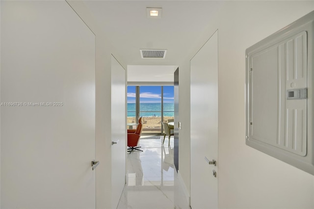 hall featuring a water view, a beach view, floor to ceiling windows, and electric panel